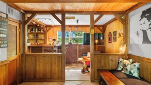 A rustic interior with wooden beams, a bar area, and a seating area with cushions. - Hideaway / Hot Tub / Sunna / Lake / Kayaks / Pool / Game Room / Cold Plunge (Pocono Mountain Lake Estates)