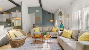 A modern living room with a sofa, a coffee table, and a wicker chair. - Hideaway / Hot Tub / Sunna / Lake / Kayaks / Pool / Game Room / Cold Plunge (Pocono Mountain Lake Estates)