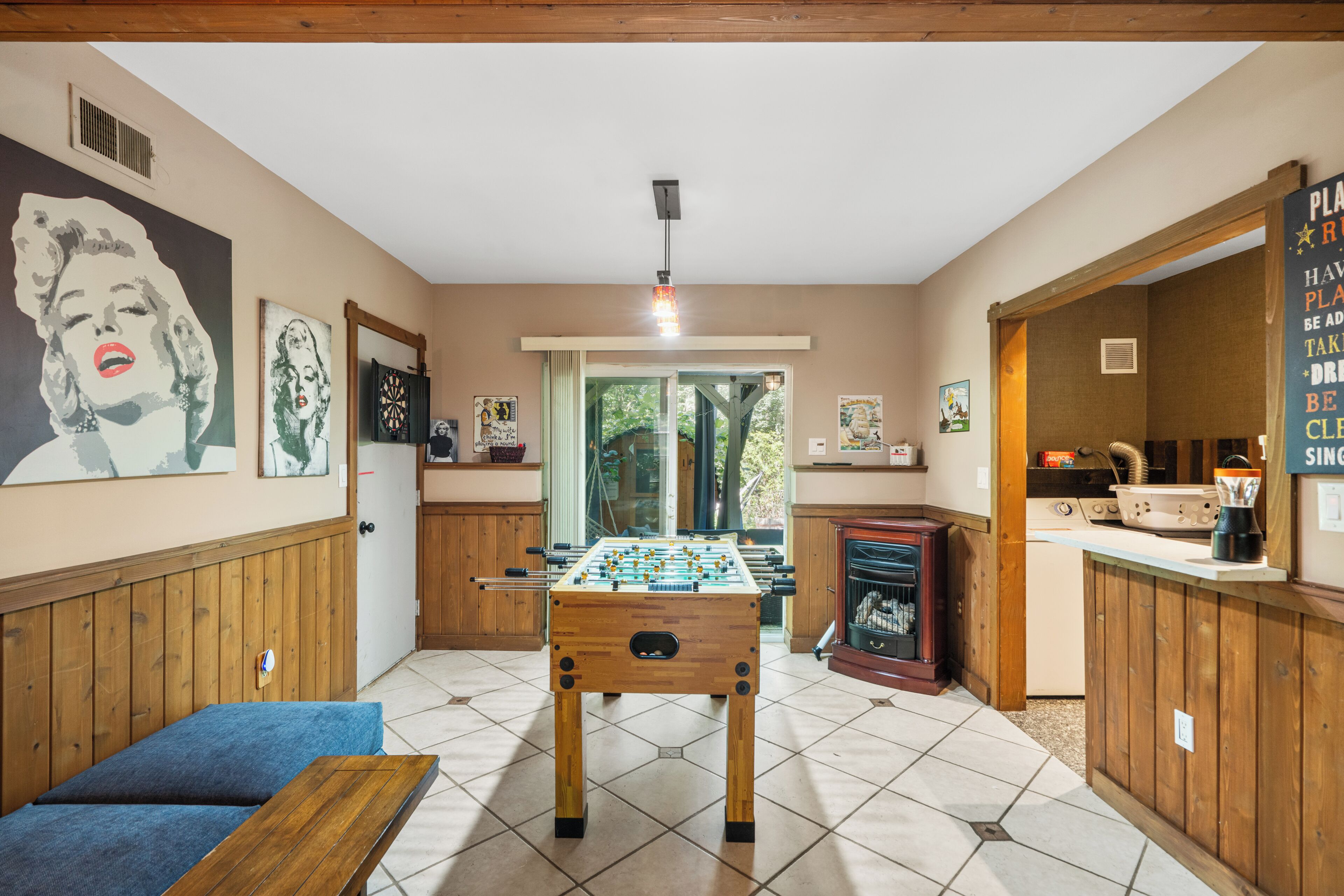 A cozy room with a foosball table, a sofa, and a kitchen area.