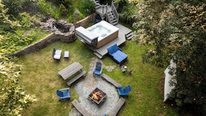 A hot tub surrounded by blue Adirondack chairs, a fire pit, and a wooden deck. - Hideaway / Hot Tub / Sunna / Lake / Kayaks / Pool / Game Room / Cold Plunge (Pocono Mountain Lake Estates)