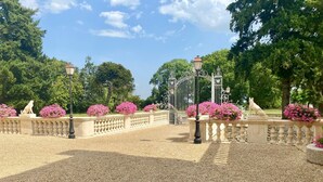 A garden with a gravel pathway, decorative lamp posts, and statues. - An enchanting chateau set in 10 hectares of wooded parkland, in absolute peace and quiet! (Les forges)