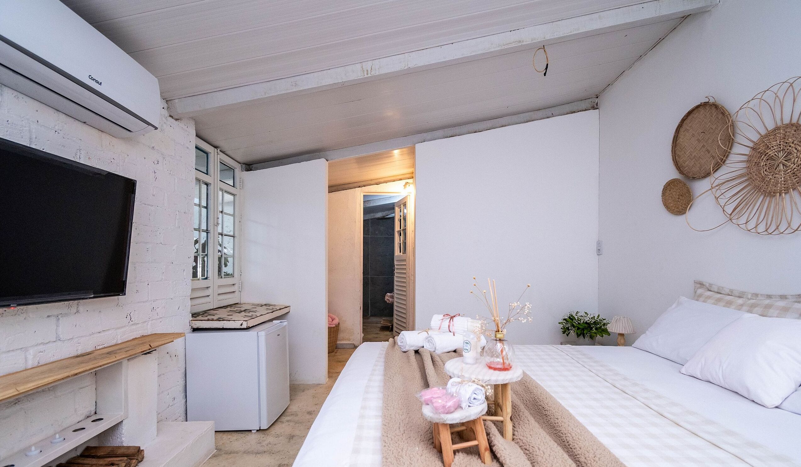 A bedroom with a bed, bedside table, and a television mounted on the wall.