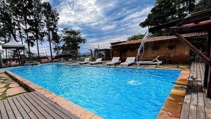 A swimming pool with lounge chairs and a wooden deck. - Cozy Lakefront Suites RGB (Hidrolandia)