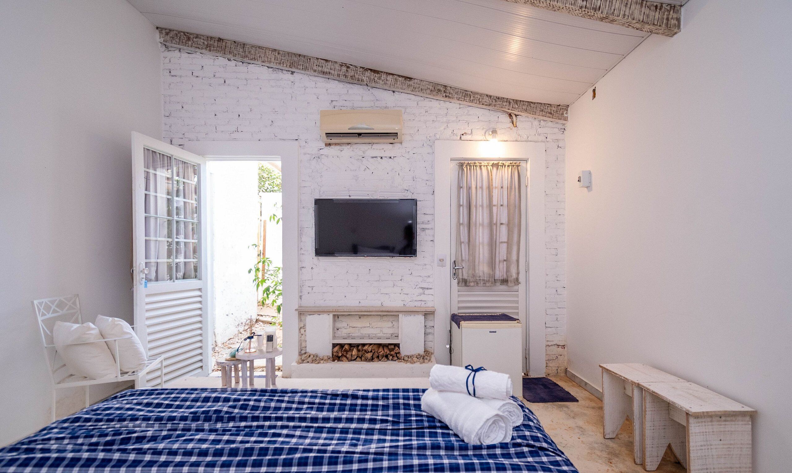A bedroom with a bed, a TV, a fireplace, and a window.
