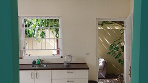 A kitchen with a window, a sink, and a trash bin.