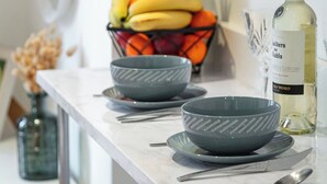 A kitchen counter with bowls, a bottle of white wine, and a fruit basket. - Charming Cozy Studio Apartment (London)
