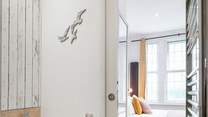 A bathroom with a toilet, a roll of toilet paper, and a wooden wall panel. - Charming Cozy Studio Apartment (London)