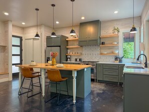 A modern kitchen with a central island, pendant lighting, and a view of the outdoors.