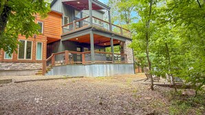 A multi-story house with a balcony, wooden deck, and stone foundation. - Ride ATVs • Luxe King Suite •  Modern-Meets-Cozy Retreat  • Prime Location (Broken Bow)