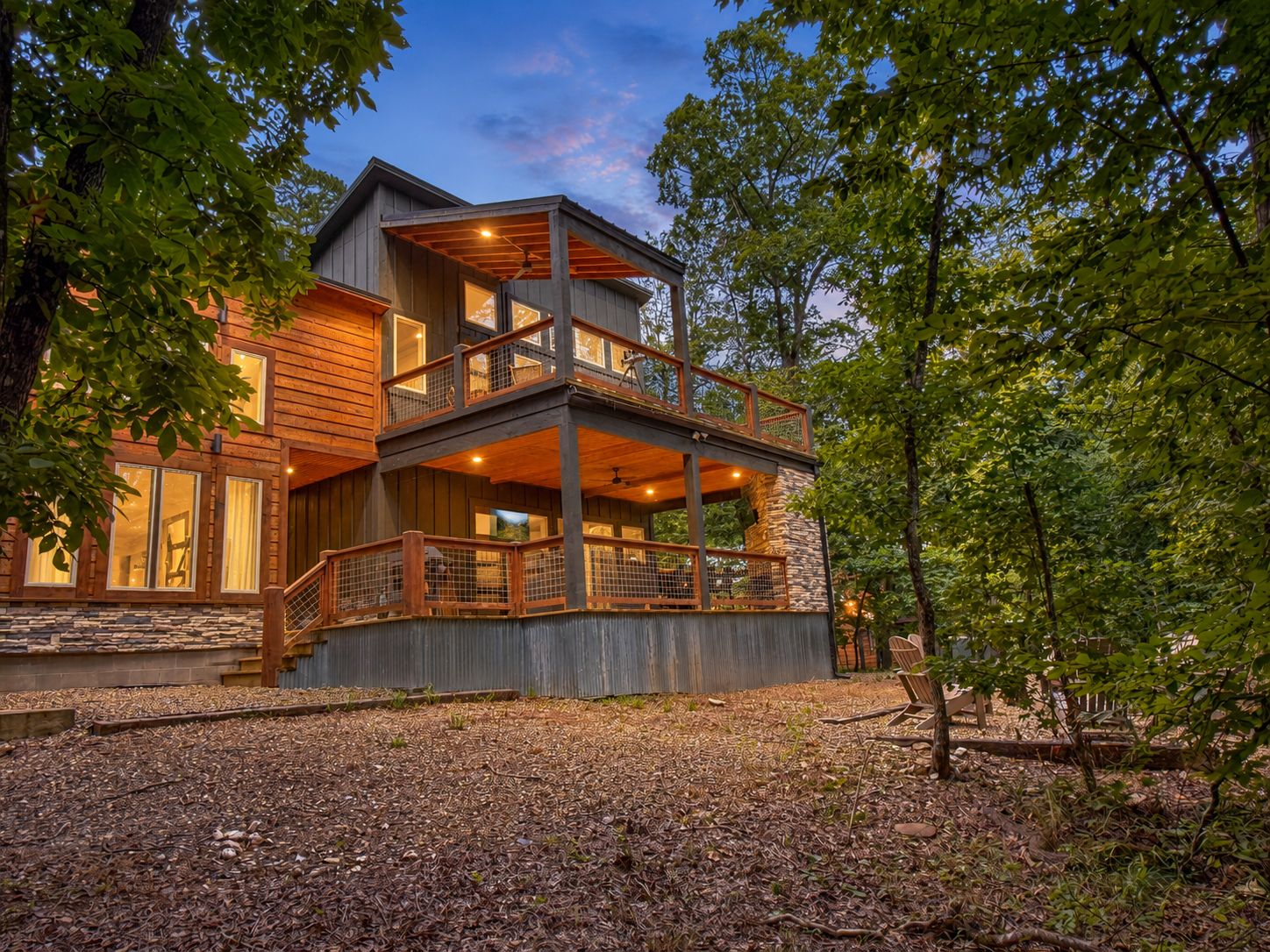 A multi-level wooden house with a balcony, surrounded by trees.