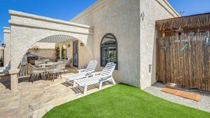 A pool house with a stone exterior, a covered patio with outdoor furniture, and a wooden fence.