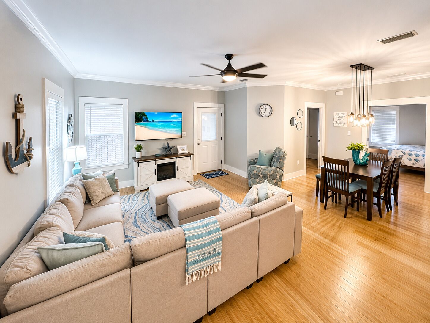 A modern living room with a large sectional sofa, a dining area with a wooden table and chairs, and a kitchen in the background.