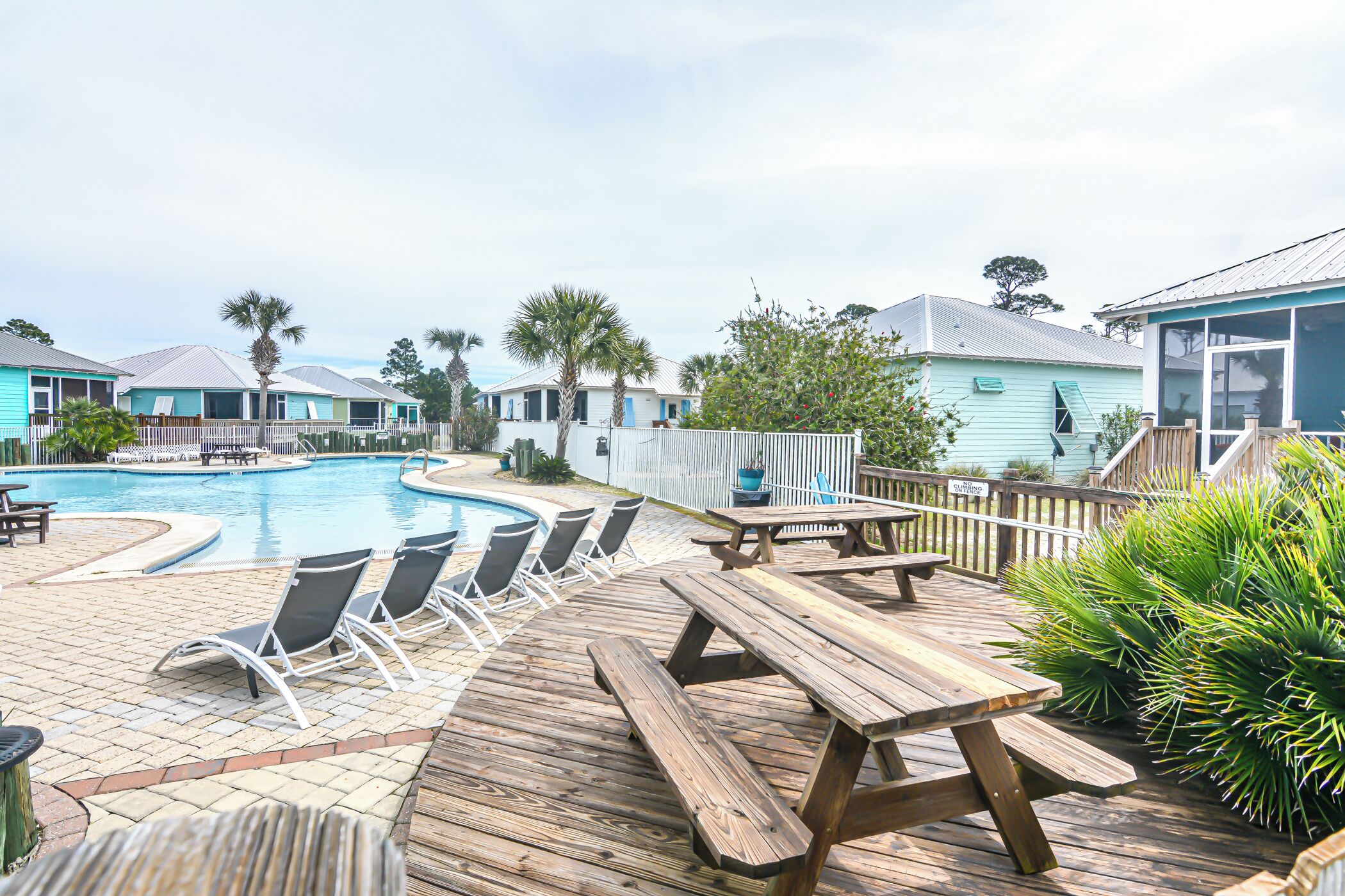A wooden deck with a pool, lounge chairs, and a picnic table.