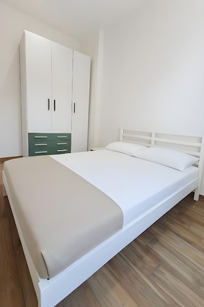 A bedroom with a bed, a wardrobe, and a wooden floor.