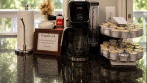 Eine Kaffeestation mit Kaffeemaschine, einer gerahmten Kaffeeanleitung und einer Kaffeebohnen-Auswahl.