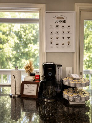 A coffee station with a coffee maker, a framed coffee guide, and a tray of coffee containers. - Seattle Escape Hot Tub,Sauna,Gym, Game Room, EV charging, massager,GROUPS (Sammamish)