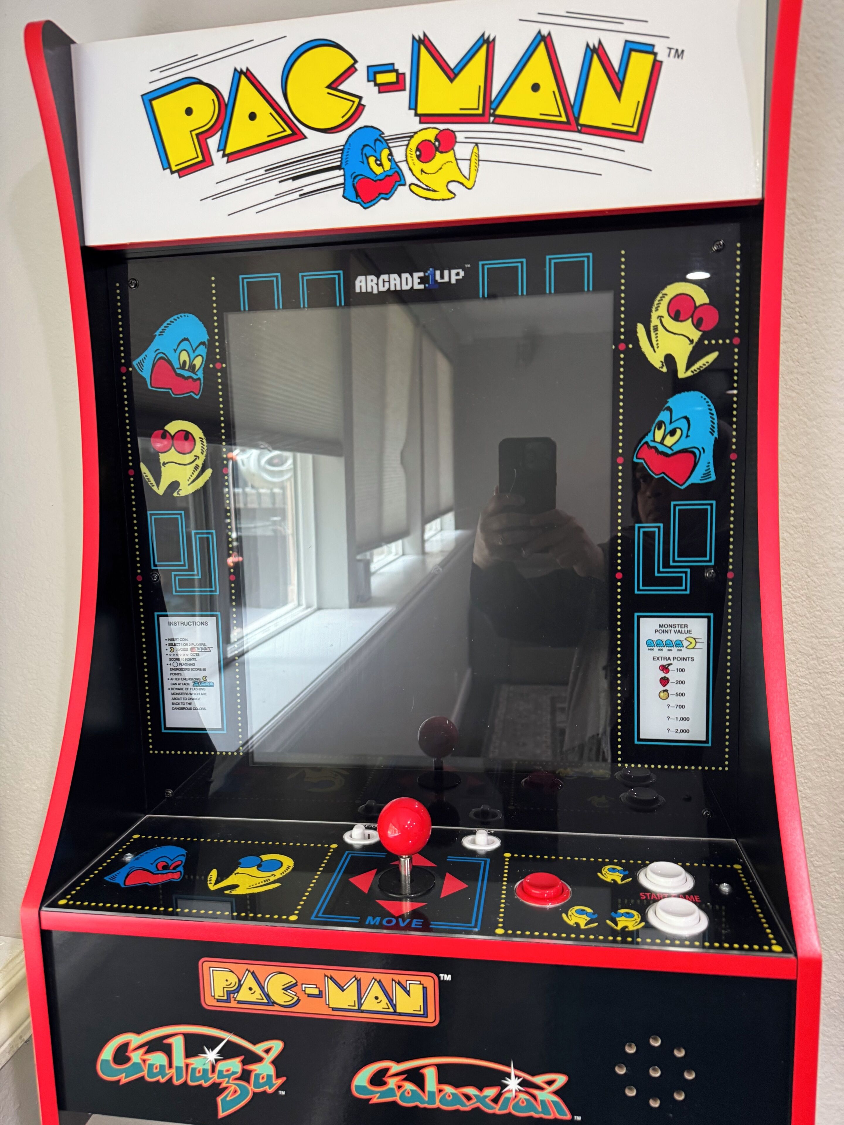 Pac-Man-peliautomaatti, jossa on peilikiiltävä pinta, ohjaussauva ja pistenäyttö.