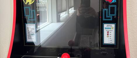 Máquina de videojuegos Pac-Man con superficie espejada, palanca y pantalla de puntaje.