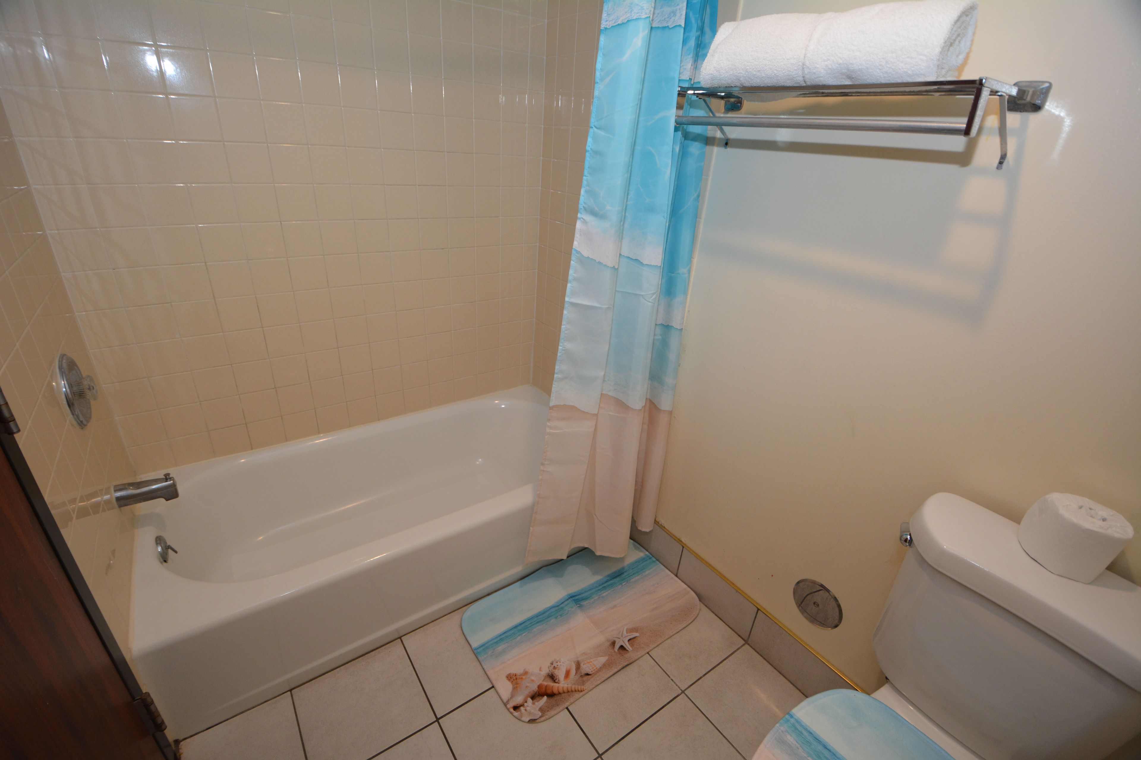 A bathroom with a bathtub, toilet, and a shower curtain.