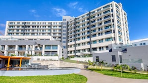 Un hôtel moderne à plusieurs étages, doté d’une cour intérieure, d’un espace extérieur aménagé et d’une piscine.