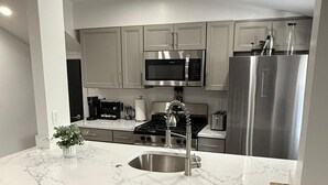 A modern kitchen with a central island, stainless steel appliances, and bar stools.