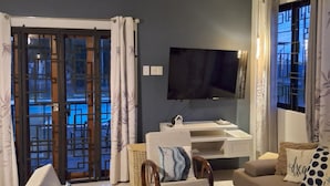Een woonkamer met een plafondventilator, een televisie, een bank en een fauteuil.