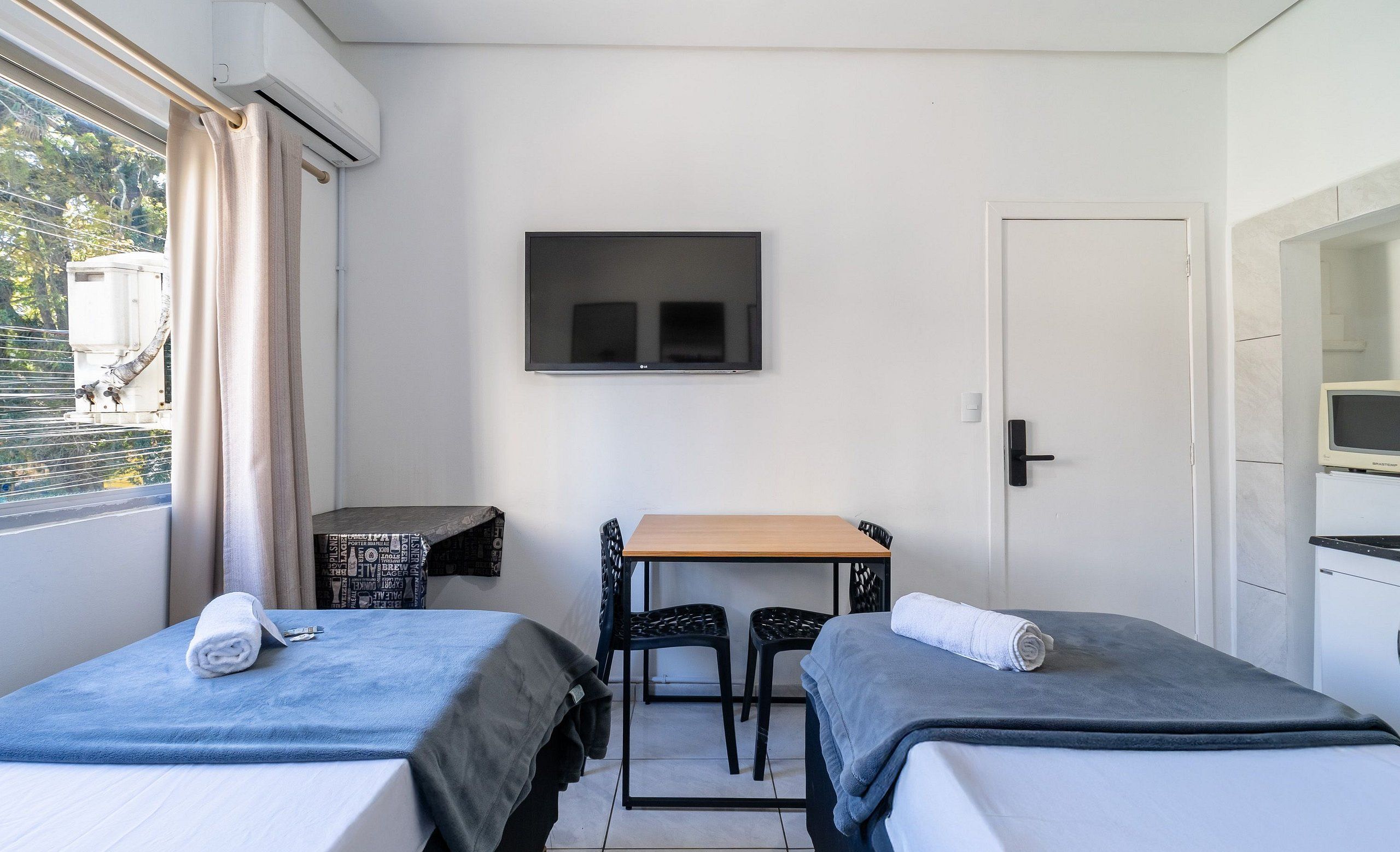 A room with two beds, a table, chairs, a TV, and a door.