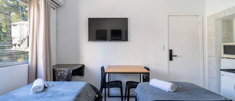 A room with two beds, a table, chairs, a TV, and a door.