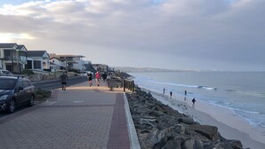 Una passeggiata costiera con un sentiero lastricato, un litorale roccioso e vista sul mare.