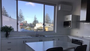 Una cucina moderna con un'ampia finestra, mobili bianchi, forno integrato e isola centrale con due sedie.