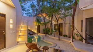 A modern outdoor pool area with a staircase leading to a covered upper level, surrounded by trees and a well-lit patio. - APSARA 3 villas condominiums top pools in beautiful Tulum (Tulum)