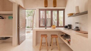 A modern kitchen with wooden stools, a built-in bar, and a large window. - APSARA 3 villas condominiums top pools in beautiful Tulum (Tulum)