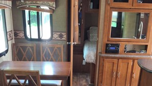 A compact RV interior with a dining area, a sofa, and a kitchenette. - Cozy Camper setup, off grid (Dunlop)