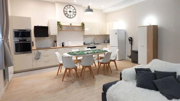 Una cocina moderna con mesa de billar, armarios blancos y un reloj en la pared.