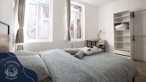 Un dormitorio ordenado con cama, armario y ventana con cortinas.