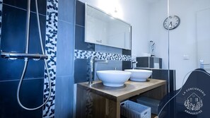 A modern bathroom with a shower, two sinks, a mirror, and a clock on the wall. - Places d'Arras • 2 ch • Parking • terrasse (Arras)