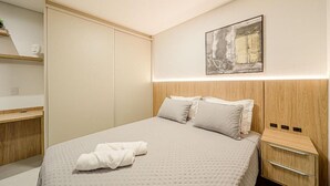 A modern bedroom with a large bed, a bedside table, a wall-mounted artwork, and a wardrobe. - Studio H Residence Studio H Residence (Joinville)