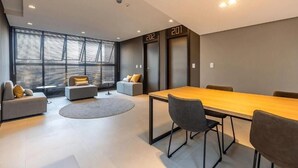 A modern meeting room with a long table, several chairs, and two sofas. - Studio H Residence Studio H Residence (Joinville)