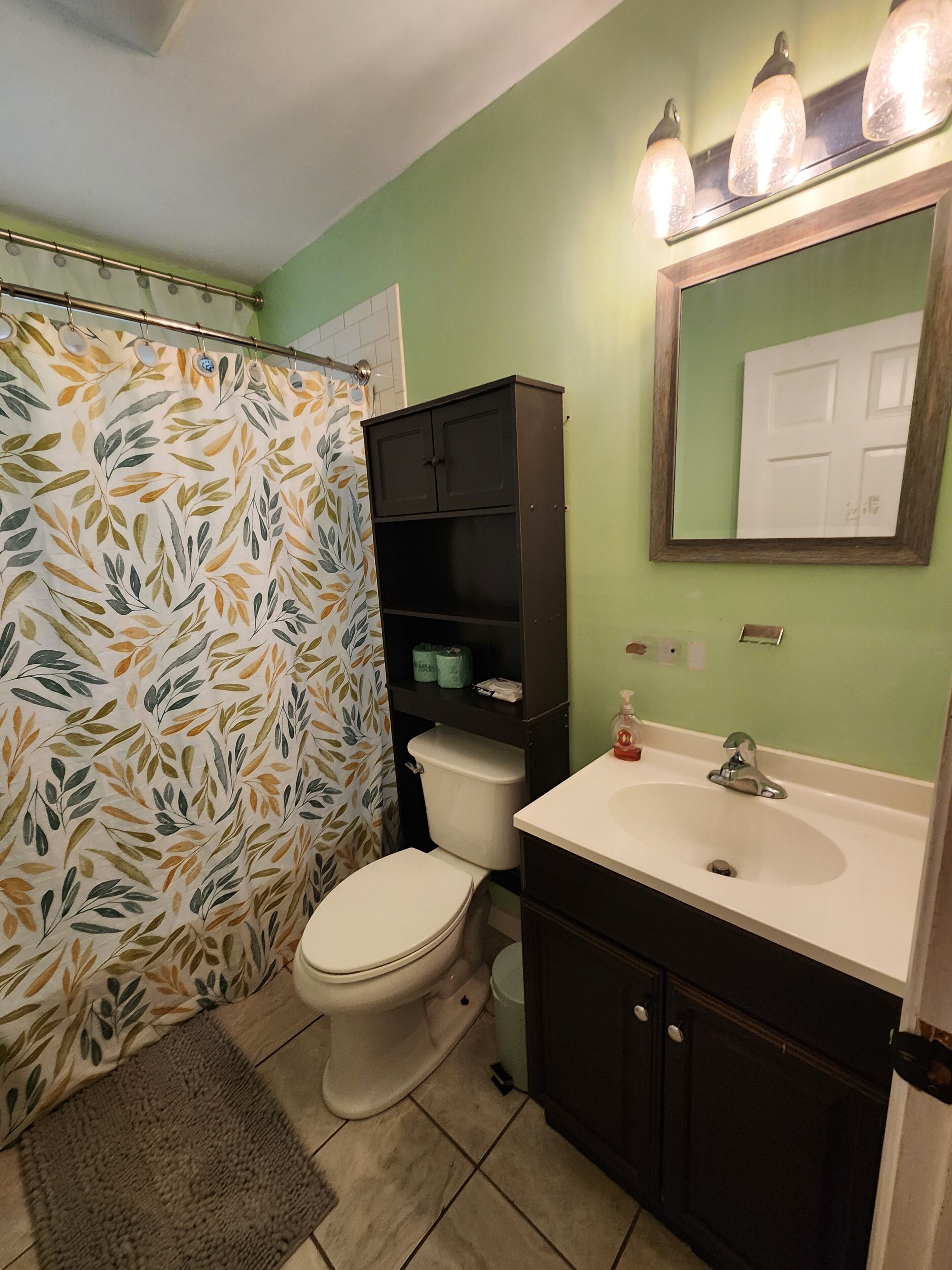 Un baño con inodoro, lavamanos y cortina de ducha.