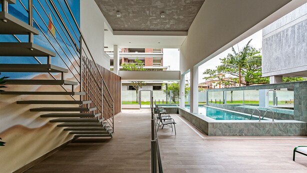 A modern indoor swimming pool area with a staircase on the left and a view of the outside buildings. - Modern duplex w/jacuzzi 240m beach JRR410 (Florianópolis)