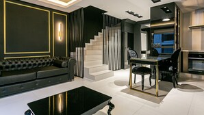 A modern living room with a black sofa, a glass coffee table, and a staircase with black and white decor. - Modern duplex w/jacuzzi 240m beach JRR410 (Florianópolis)