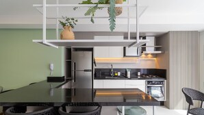 A modern kitchen with a central island, black chairs, and a hanging plant. - Modern duplex w/jacuzzi 240m beach JRR410 (Florianópolis)