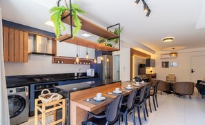 Una cocina moderna con una isla central, electrodomésticos integrados e iluminación colgante.