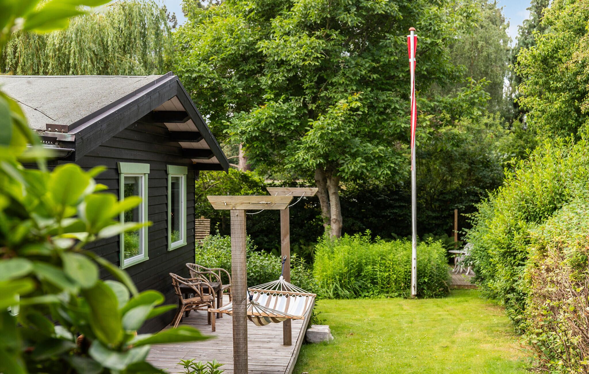 Una casa con terraza, una hamaca y un asta de bandera.