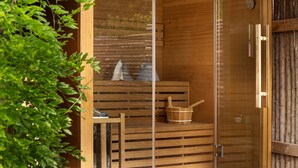 A sauna with wooden benches, a wooden bucket, and a glass door. - Amazing home in Melby with sauna (Melby)