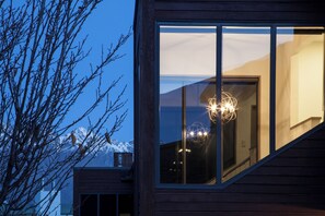 A modern building with large windows, a visible staircase, and a mountain view.