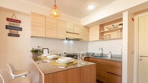 A modern kitchen with wooden cabinets, a central island with a glass top, and a hanging pendant light.