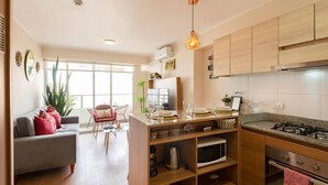 A modern kitchen with wooden cabinets, a gas stove, and a dining area with a sofa and chairs.