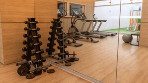 A gym with various exercise equipment, including dumbbells, a bench press, and treadmills.