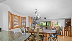 A spacious dining area with a granite countertop, wooden chairs, and a chandelier.